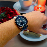 The LUQ Rose Gold Watch styled for an elegant dinner setting, featuring a 45mm rose gold case, navy blue dial, and premium leather strap. A luxurious timepiece perfect for special occasions.