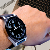 The LUQ Stainless Steel Watch shown in a professional workspace setting, with a bold 45mm stainless steel case, black dial, and leather strap. Ideal for professionals and everyday wear.